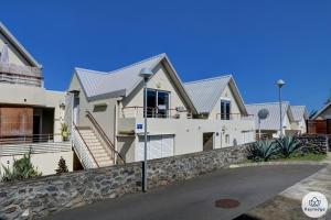a large white house with a stone wall at T2 - Cantebazi 3 étoiles- plage de Saint-Leu in Saint-Leu