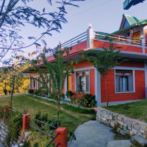 a red house with a garden in front of it at Oak Essence in Mukteshwar +22 photos