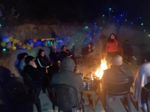 a group of people sitting around a fire at night at Oak Essence in Mukteshwar