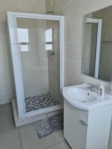 a white bathroom with a shower and a sink at @Anderson Executive Suites in Kimberley