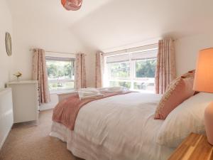 a bedroom with a white bed and two windows at Roseville in Matlock