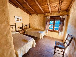 a bedroom with two beds and a window at Finca El Molino De Aceite in Jubrique