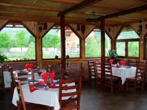a dining room with tables and chairs and windows at Pensiunea Micutul Vrajitor in Arefu