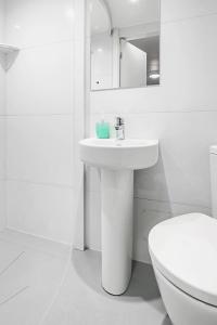 a white bathroom with a sink and a toilet at Astor Kensington Hostel in London