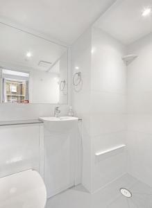 La salle de bains blanche est pourvue d'un lavabo et de toilettes. dans l'établissement Astor Kensington Hostel, à Londres