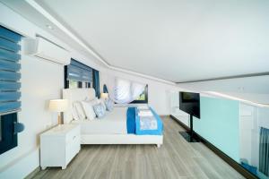 a bedroom with a white bed and a flat screen tv at Ilias Suites in Skala Potamias