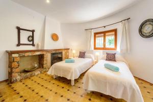 two beds in a room with a fireplace at Villa Rosa in Sant Josep de sa Talaia
