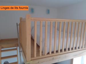 Una cuna de madera en una habitación con una pared blanca en Appartement rez de chaussée avec terrasse et jardin, en Tence