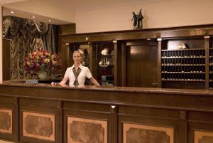 a woman in a tie standing behind a bar at Hotel Horizont in Baška Voda