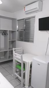 a white kitchen with a white table and chairs at Pousada Verdes Mares guaratuba in Guaratuba