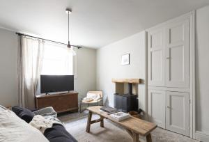 a living room with a couch and a tv and a table at Round House Cottage in Castle Cary