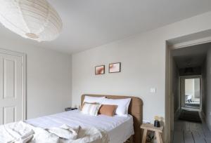 um quarto branco com uma cama com lençóis e almofadas brancos em Round House Cottage em Castle Cary
