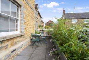 eine Terrasse mit einem Tisch und Stühlen neben einem Gebäude in der Unterkunft Round House Cottage in Castle Cary