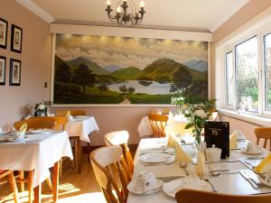 a dining room with tables and a painting on the wall at Adare Guesthouse in Galway
