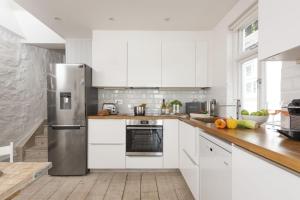 eine Küche mit weißen Schränken und einem Edelstahlkühlschrank in der Unterkunft Upper Chandlers Cottage in Mousehole