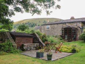 a garden with a stone house and a table and bench at Nuthatch Cottage in Skipton