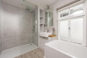 ein weißes Badezimmer mit Badewanne und Waschbecken in der Unterkunft Upper Chandlers Cottage in Mousehole + 18 Fotos