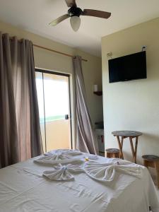 um quarto com uma cama, uma ventoinha de tecto e uma janela em Pousada Muzy em Barra de São João