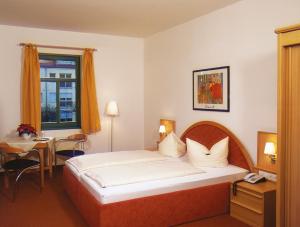 ein Hotelzimmer mit einem Bett, einem Tisch und einem Fenster in der Unterkunft Gutshof Hauber in Dresden