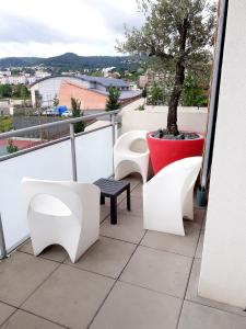 einen Balkon mit weißen Stühlen und einem Baum darauf in der Unterkunft DÉTENTE GARANTIE in Clermont-Ferrand