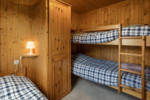 two bunk beds in a wooden cabin with a lamp at L étincelle du Manon in Lajoux