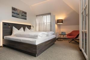 a bedroom with a bed and a red chair at Hotel Spitzerberg by b-smart in Hundsheim