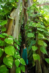 a woman standing next to a tree in a forest at Kuramathi Maldives in Rasdhoo