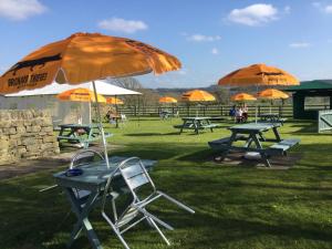 eine Gruppe Picknicktische mit einem Sonnenschirm in der Unterkunft Rose & Crown in Slaley