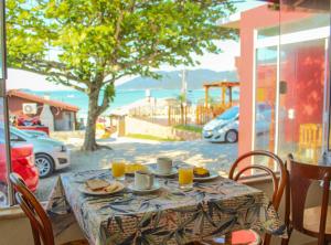 a table with plates of food and orange juice on it at Pousada Estrelas no Mar Florianópolis in Florianópolis