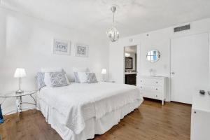 a white bedroom with a bed and a table at Renovated cozy The yacht club at aventura Parking included in Miami