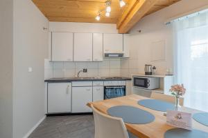 cocina con armarios blancos y mesa de madera en Efeu, en Interlaken