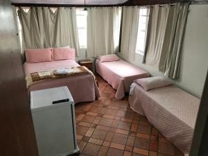 a small room with two beds and a window at Pousada Acayaca in Diamantina