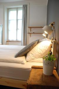 ein Schlafzimmer mit einem Bett mit einer Lampe und einer Pflanze auf einem Tisch in der Unterkunft The Bed + Breakfast in Luzern
