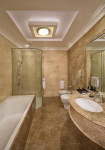 a bathroom with two sinks and a tub and a toilet at Royal Rose Hotel in Abu Dhabi