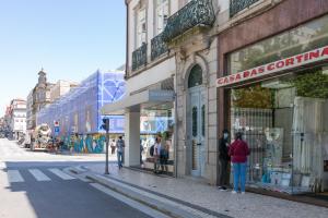 um grupo de pessoas em pé em frente a lojas em uma rua em BO - Fernandes Tomás no Porto