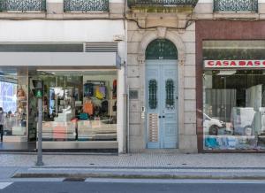 uma frente de loja com uma porta azul numa rua em BO - Fernandes Tomás no Porto