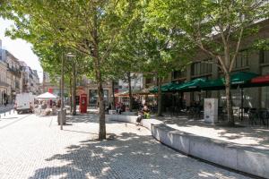 a street with trees and people sitting on a sidewalk at BO - Fernandes Tomás in Porto