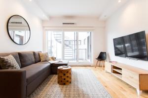 uma sala de estar com um sofá e uma televisão de ecrã plano em Hip, Stylish Apartment in Little Italy by Den Stays A em Montreal