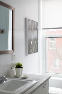 une salle de bain blanche avec un lavabo et une fenêtre dans l'établissement Trendy Little Italy 3 Bedroom Condo by Den Stays, à Montréal