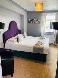 a bedroom with a large bed with a purple headboard at The Traxx Hotel in Bangor