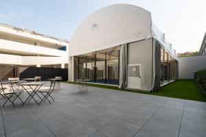 a large white building with tables and chairs on a patio at Camplus Regio Parco in Turin