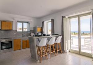 a kitchen with a bar with white stools at Olive Garden Luxury Resort in Angairiá