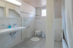 a white bathroom with a sink and a toilet at Mohn in Interlaken +15 photos
