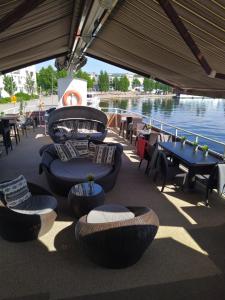 eine Terrasse mit Tischen, Stühlen und Wasser in der Unterkunft Hotellilaiva Wuoksi in Kuopio