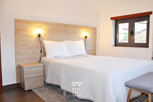 een slaapkamer met een groot bed met 2 verlichting bij Refúgio do Alva - Serra da Estrela in Seia