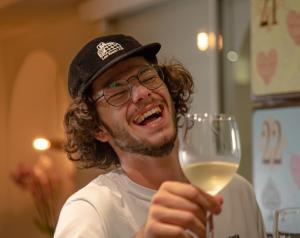 a man holding a glass of white wine at GRAND your home with common kitchens with self check-in in Engelberg