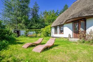 two benches sitting in the grass in front of a house at Fischerhus Ummanz FW2 in Ummanz