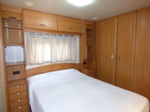 a bedroom with a white bed and a window at Camping Barraquetes in Sueca