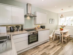 a kitchen with white cabinets and a table at Bryn Hafod in Cemaes Bay