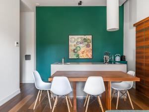 comedor con pared verde, mesa de madera y sillas blancas en numa I Vita Apartments, en Florencia
